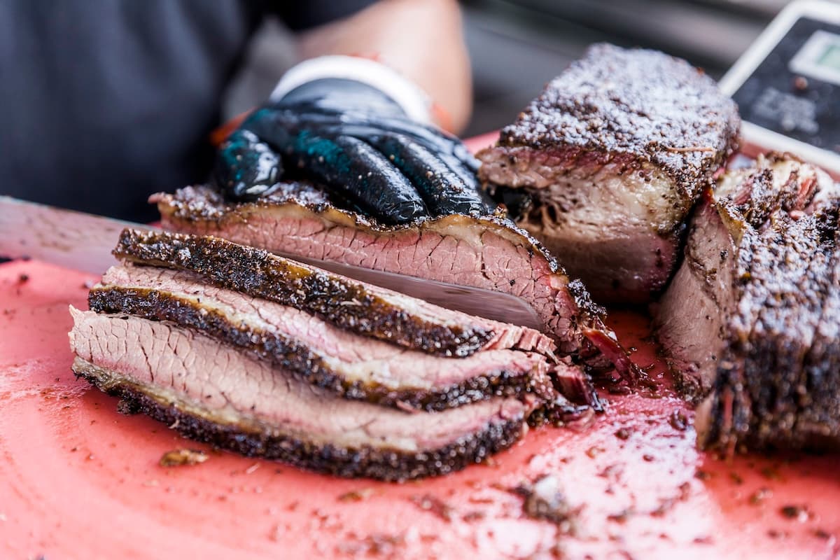 Brisket being cut on a cutting board