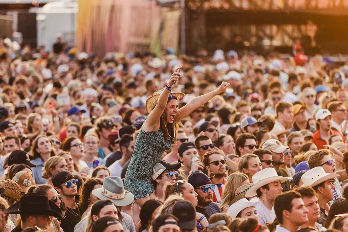 a woman sitting on a man's shoulders, towering over a large crowd of people